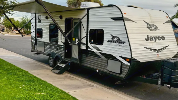 This Jayco travel trailer RV rental is parked on a residential street with its awning extended, ready for adventure.. Jayco Jay Flight SLX 2022