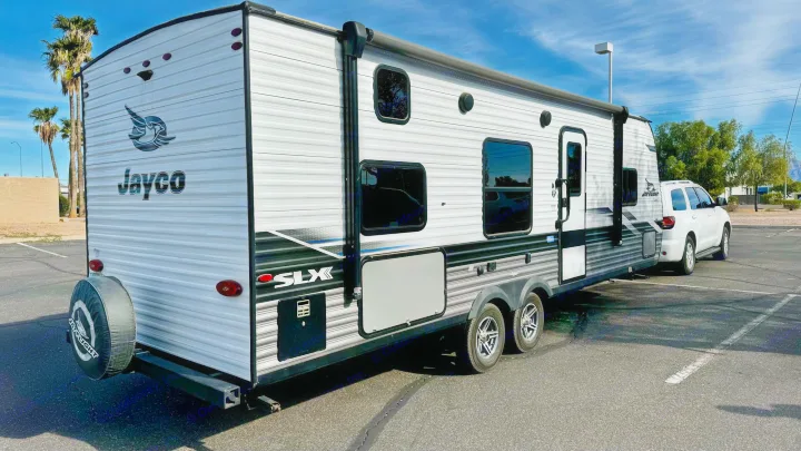 Jayco SLX travel trailer RV rental, grey & white, with a white SUV parked in a sunny lot. Rear view.. Jayco Jay Flight SLX 2022