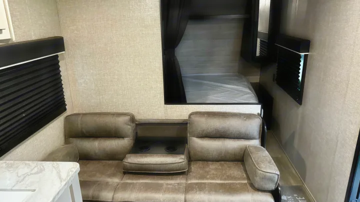 RV rental interior featuring a versatile sofa with cupholders and a cozy bunk bed area with privacy curtain.. Jayco Jay Flight SLX 2022