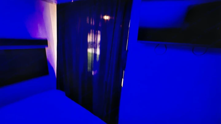 Blue-lit RV rental interior: modern bedroom with bed shelves, dark curtains, and wall-mounted TV. Cozy and futuristic feel.. Jayco Jay Flight SLX 2022