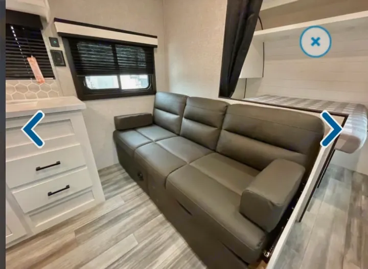 RV rental interior featuring a gray sofa that converts to a bed, a pull-down bunk, and clever space-saving design.. Jayco Jay flight 2024