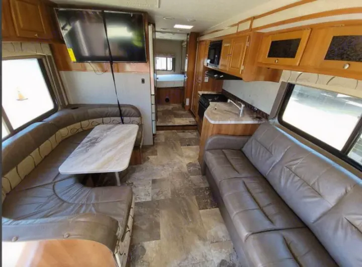 RV rental interior showcasing a modern kitchen, comfortable sofa, and dinette with TV.. Other Other 2019