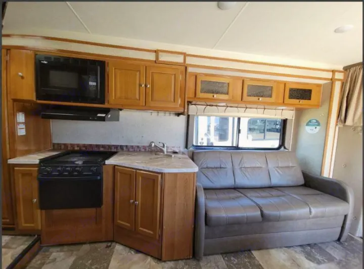 Explore this RV rental! Features a fully equipped kitchen with stove, microwave, sink, plus a comfy sofa.. Other Other 2019