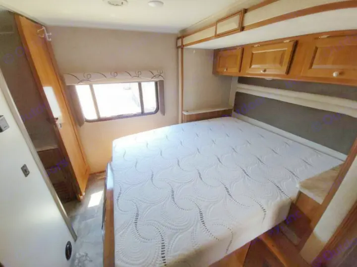 An RV rental bedroom showcasing a comfortable bed with a patterned mattress, overhead cabinets, and a side window.. Other Other 2019