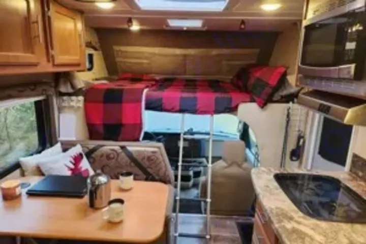 Class C RV rental interior features a cozy bed, dinette, and kitchen, ideal for travel adventures.. Adventurer Adventurer Motorhome 2017