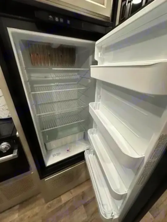 Clean, empty RV rental refrigerator with multiple wire shelves & door storage, ready for your groceries.. Jayco Greyhawk 2023