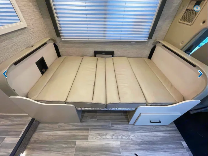 RV rental interior featuring a versatile dinette that converts into a comfortable bed with integrated storage, below a window with blinds.. Thor Freedom Elite 2023