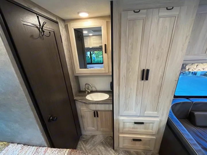 Explore this RV rental's compact interior featuring a vanity, sink, storage cabinets, and comfortable seating.. Forest River Sunseeker LE 2022