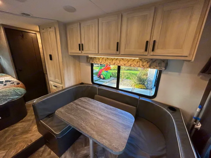 Explore this RV rental's inviting interior: U-shaped dinette, ample storage cabinets, and scenic window view.. Forest River Sunseeker LE 2022