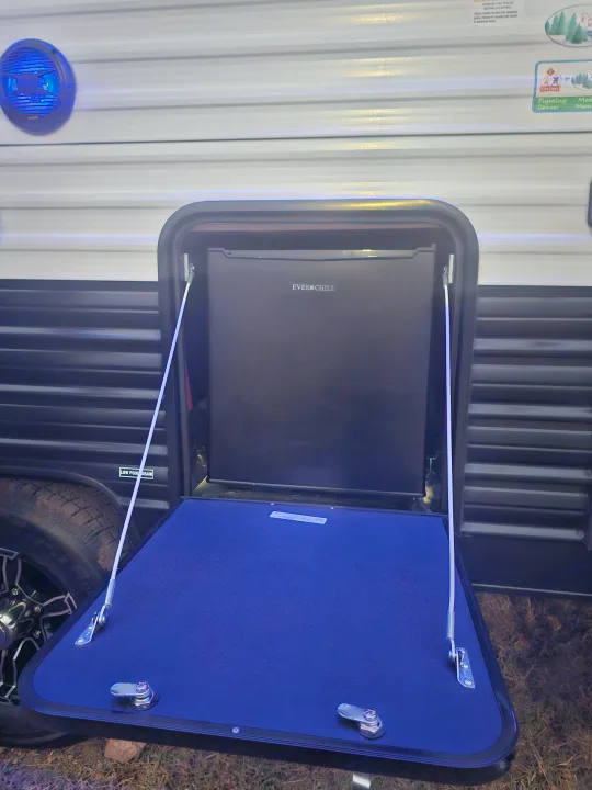 RV rental outdoor kitchen setup featuring an Ever Chill mini-fridge and fold-down table, great for camping adventures.. Forest River Cherokee Wolf Pup 2023