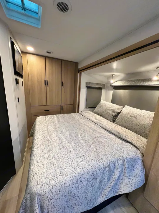 Comfortable RV rental bedroom interior with modern decor, built-in storage, and a patterned bed.. Forest River Sunseeker 2024