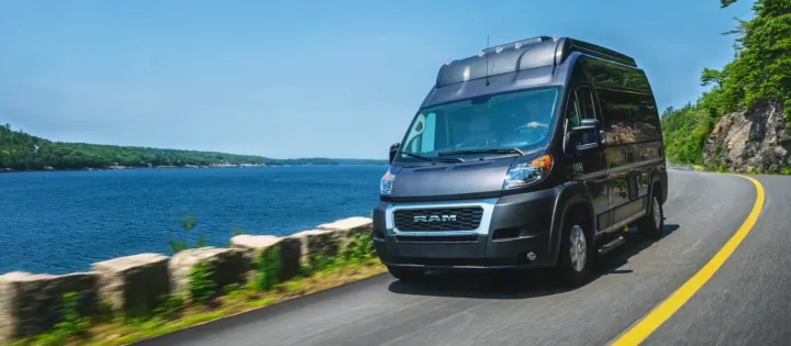 Dark grey Ram ProMaster RV rental on a scenic coastal road with ocean views.. Thor Scope 2023