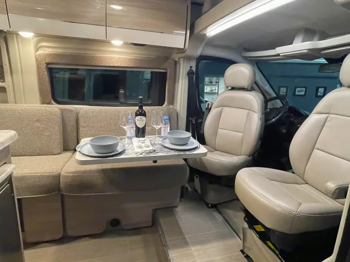 Experience comfort in this RV rental! Interior shows a dining area with wine, plus swivel front seats.. Thor Scope 2023