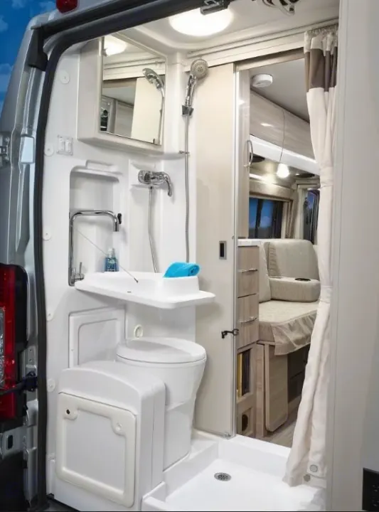 Inside an rv rental: a modern wet bath featuring a shower, toilet, and collapsible sink, with the living space beyond.. Thor Scope 2023