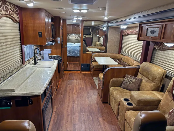 Spacious RV rental interior: modern kitchen, dining booth, cozy recliners, & bedroom visible.. Forest River Coachmen Leprechaun 2015