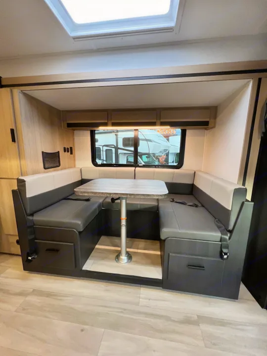 Cozy RV rental dinette featuring gray U-shaped seating, a light table, and window. Ideal for compact camper travel.. Forest River Sunseeker 2024