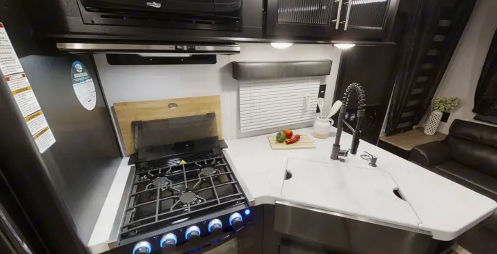 This RV rental features a modern, compact kitchen with a gas stove, deep sink, and ample counter space for cooking.. Forest River Cherokee Grey Wolf 2022