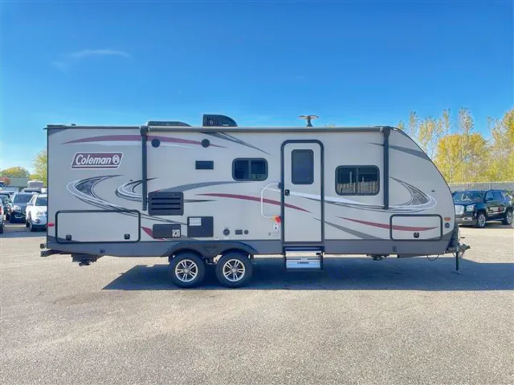 Explore in this light gray Coleman travel trailer RV rental, featuring an extended awning. Parked on asphalt.. Coleman 2305QB 2018