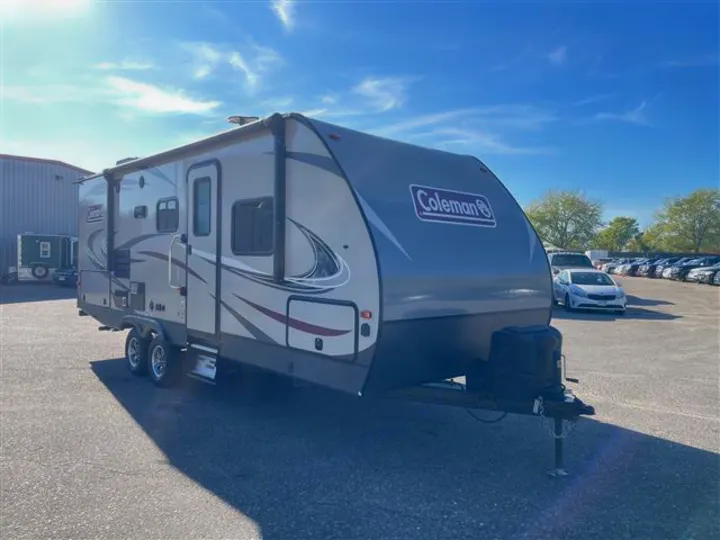 This gray Coleman travel trailer is ready for rv rental, parked on asphalt under a sunny blue sky.. Coleman 2305QB 2018