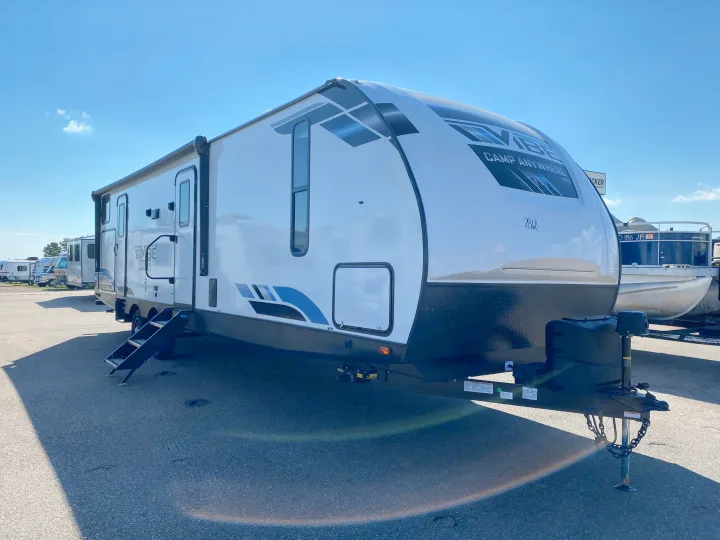 A bright white travel trailer, a perfect RV rental, with steps down, parked on a sunny paved lot.. Forest River Vibe 2021