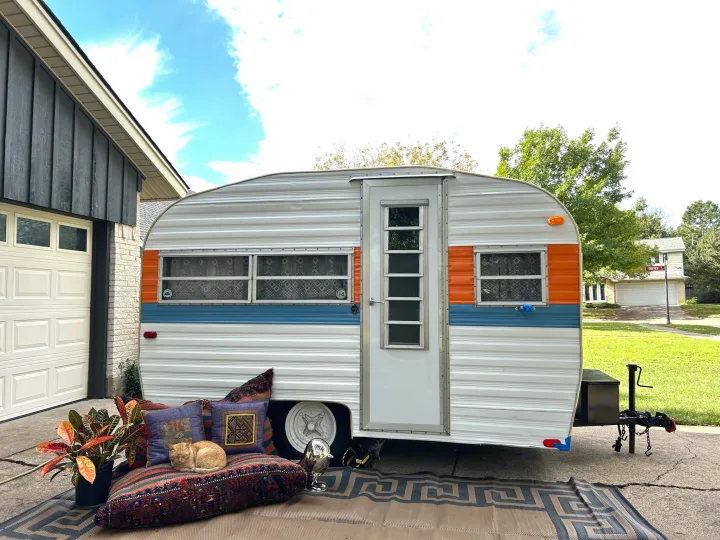 Retro RV rental parked, with a ginger cat sleeping on a patterned cushion and a potted plant.. Play-Mor Other 1978