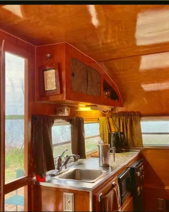 Charming RV rental kitchen with polished wood interior, stainless sink, and windows overlooking scenic views.. Play-Mor Other 1978