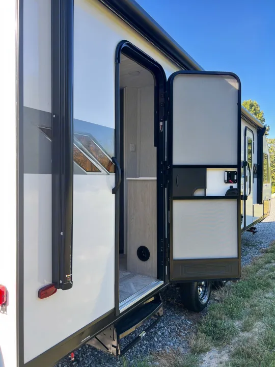An RV rental's side, with main and screen doors open, revealing a clean interior. Ideal for your next road trip!. Forest River Wildwood X-LITE 240BHXL 2024