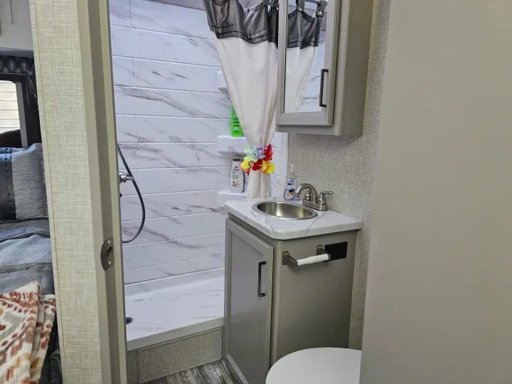 RV rental bathroom: Marble-look tiled shower, vanity with sink, and toilet. A compact, modern space.. Other Other 2024