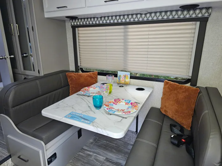 Inside this RV rental, a stylish dinette area with bench seating and a marble-look table, great for your recreational vehicle.. Other Other 2024
