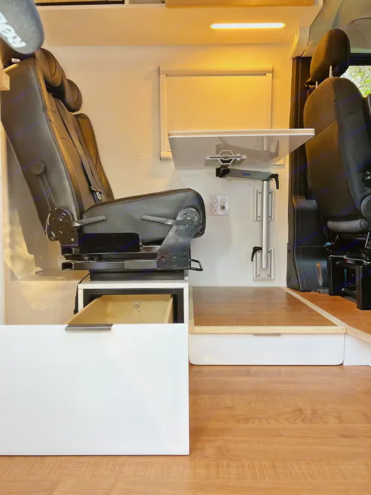 Inside this modern rv rental: a comfy swivel seat, flexible table, and built-in storage drawers. Ideal for road trips!. RAM Promaster 3500 extended wheel base 2023