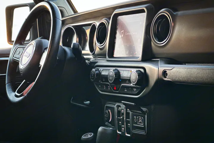 Modern Jeep dashboard: steering wheel, infotainment screen (showing 'Connect Device'), and climate controls. Ideal for RV rental trips.. Jeep Gladiator 2022