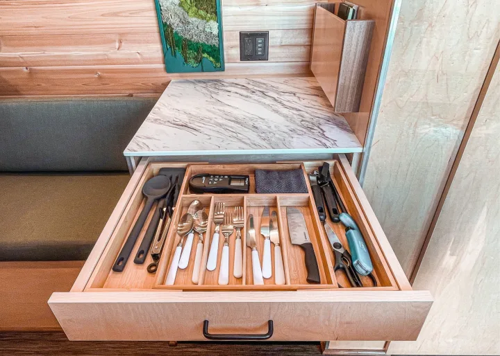This RV rental features an open kitchen drawer revealing organized utensils, flatware, and cooking tools for efficient storage.. Ram Promaster 2021