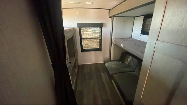 View of an RV rental bunkhouse with two bunk beds and a small sofa. The window offers natural light in this modern camper.. Heartland RVs Mallard 2021