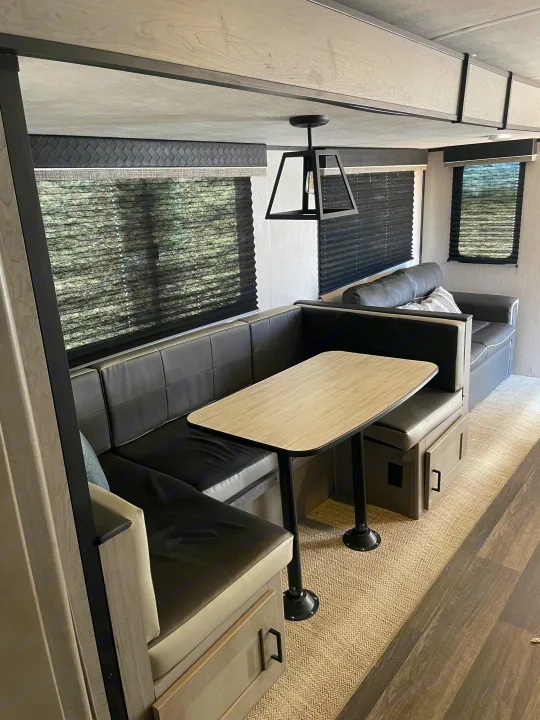 Spacious RV rental featuring a stylish dinette with dark upholstery, light wood table, and built-in storage.. Heartland RVs Mallard 2021