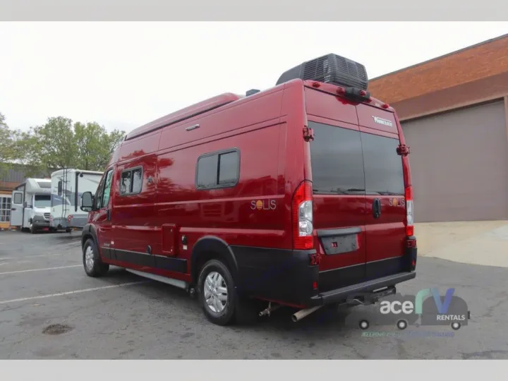 This bright red Winnebago Solis camper van, a perfect rv rental, is ready for your next adventure. Parked at a facility.. Winnebago Solis 2021