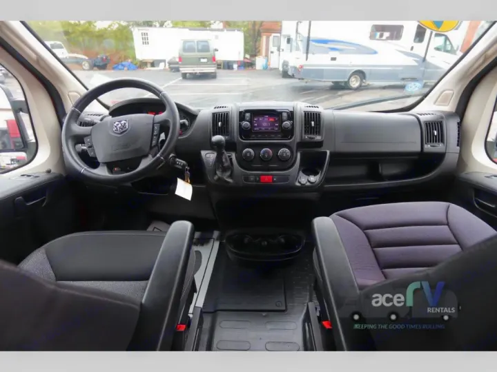 Inside this RV rental: a spacious driver's cockpit featuring the steering wheel, dashboard, and comfortable front seats.. Winnebago Solis 2021