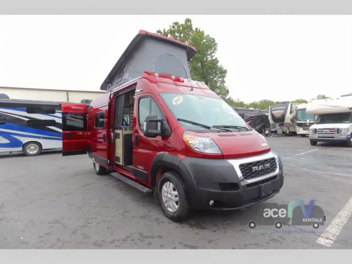 A red 2021 Winnebago Solis pop-top camper van, with its side door open, available for RV rental.. Winnebago Solis 2021