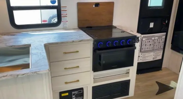 Modern RV rental kitchen showcasing a stove, oven, sink, and ample countertop space for comfortable travel cooking.. Forest River Surveyor Legend 202RBLE 2024