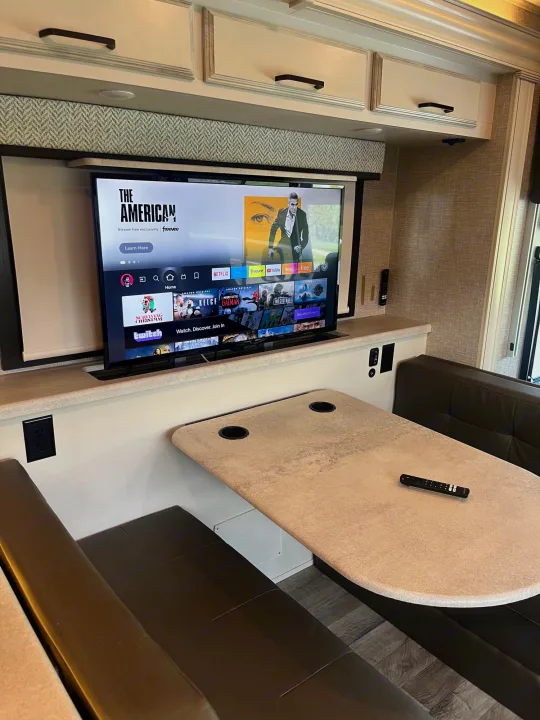 Comfortable RV rental interior: relax with entertainment on the TV (Freevee, Netflix), a dining booth, and convenient power outlets.. Entegra Vision 2023