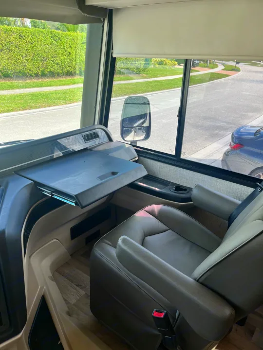 RV rental interior: driver's area with dashboard, pull-out table, captain's seat. Ready for motorhome travel.. Entegra Vision 2023