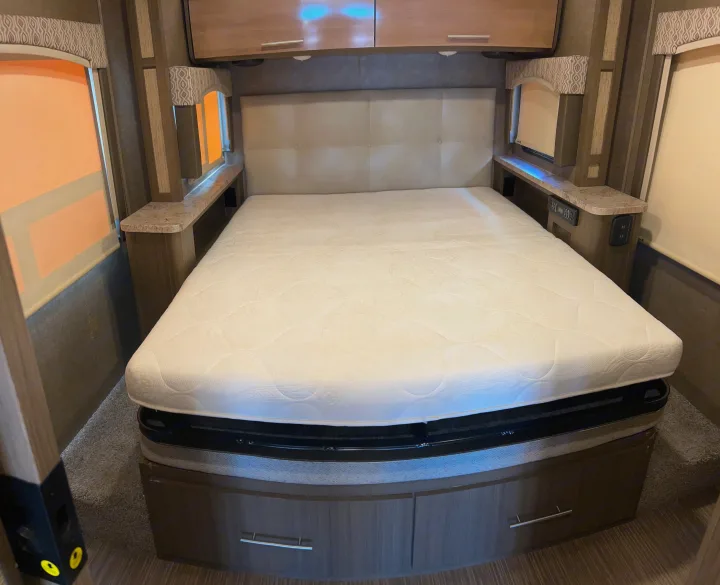 Comfortable RV rental bedroom with a queen mattress, plush headboard, and integrated storage.. Thor Motor Coach Vegas 2018