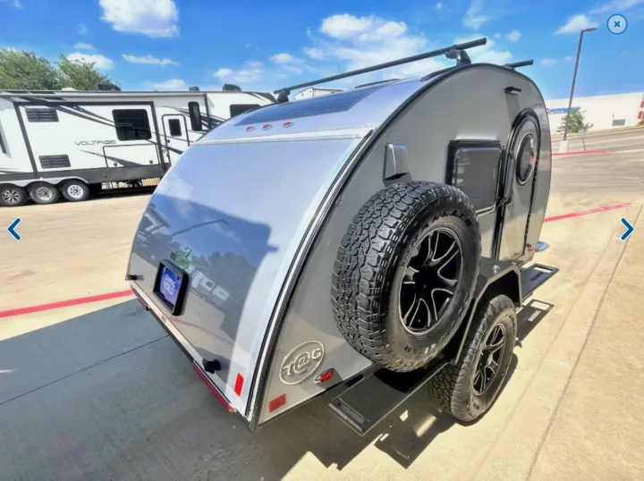Explore off-grid adventures! This silver teardrop camper with a solar panel and spare tire is perfect for RV rental.. T@G XL Boondocks 2023