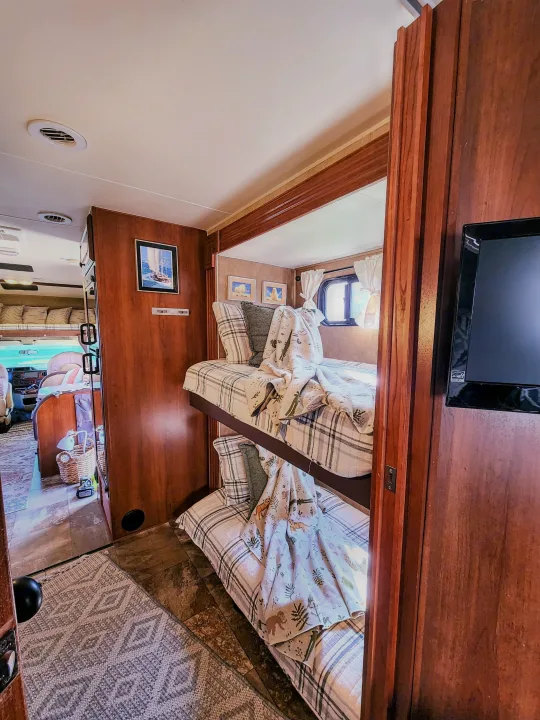 Cozy RV rental interior featuring comfortable bunk beds, a TV, and a spacious living area, ideal for family travel.. Coachmen Leprechaun 320BH 2014