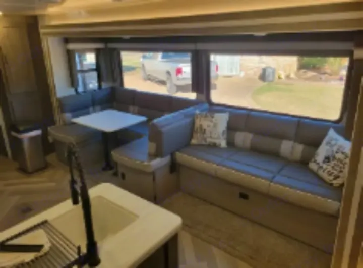 RV rental interior: U-shaped dinette, sofa, and kitchen with sink, offering a comfortable & functional living area for travelers.. Forest River Wildwood 2022