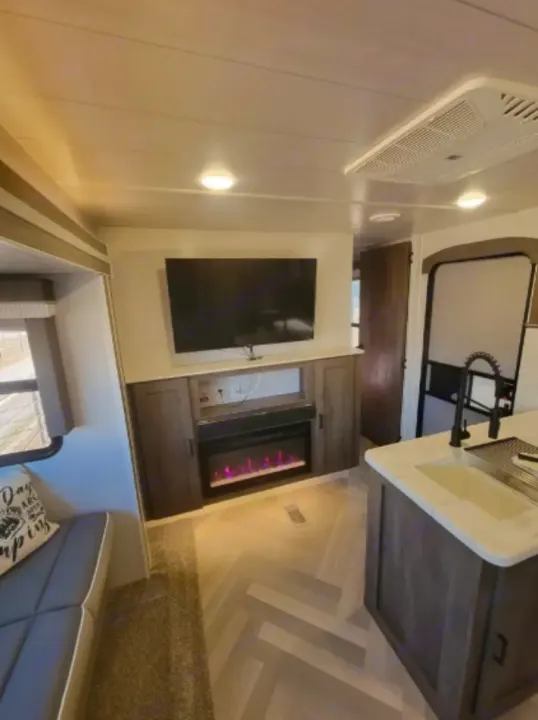 Explore this RV rental: Features a cozy living area with TV, electric fireplace, and kitchen island.. Forest River Wildwood 2022
