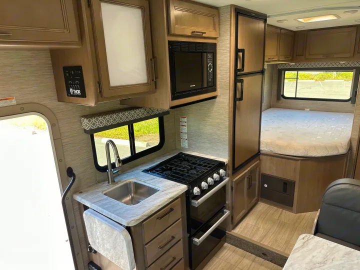 RV rental interior: Kitchenette with sink, stove, microwave, fridge, and cozy bedroom. Ideal for road trips.. Coleman 22EQ 2022