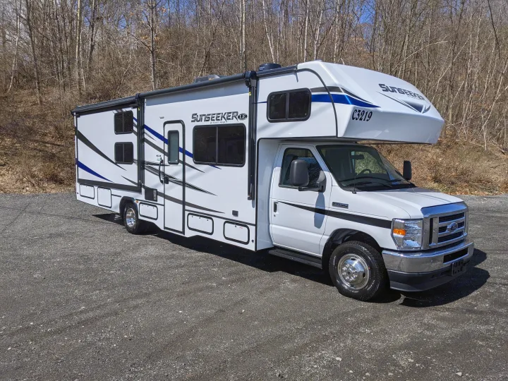 A shiny white Sunseeker Class C motorhome, perfect as an rv rental, is parked outdoors on a sunny day.. Forest River Sunseeker 2025