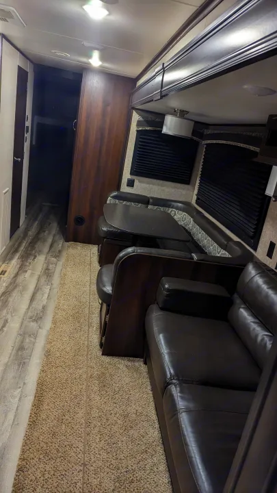 Spacious RV rental interior, showing a dinette with booth seating, sofa, and wood-look flooring. Ready for your next journey.. Jayco Jay Flight 2018