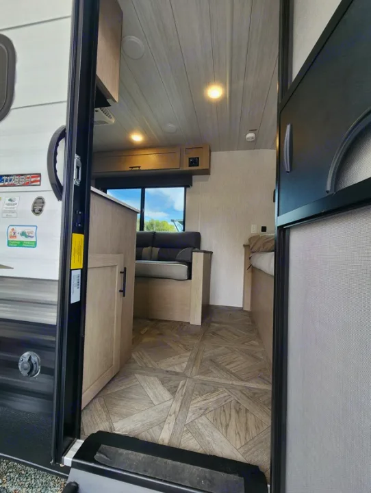 Inside an RV rental: View from the entry showing a patterned floor, wood ceiling, and living area with a large window.. Other Other 2024