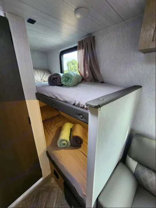 Cozy RV rental bunk beds: a neatly made interior sleeping area with two bunks, window, and rolled blankets.. Other Other 2024